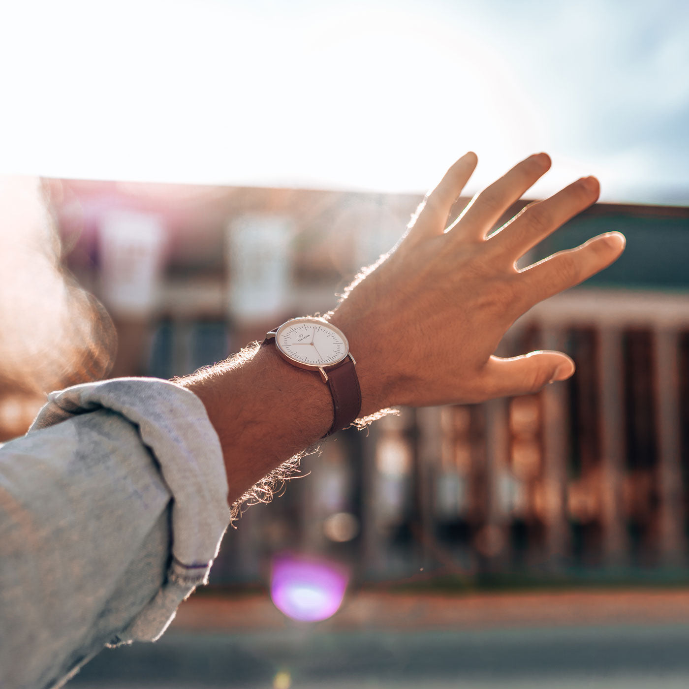 Ausgestreckter Arm im Gegenlicht mit SPARK Solaruhr am braunen Lederarmband